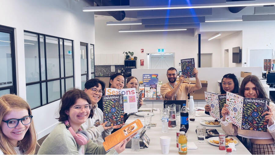 Participants of the Universal Magazine committee posing with previous published editions.