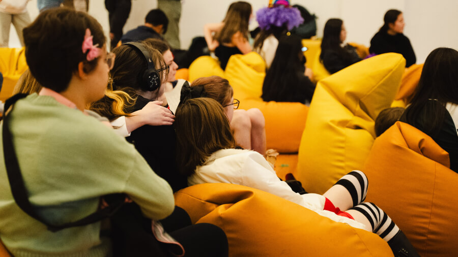 Crowd sitting on bright yellow bean bags while enjoying the performers.