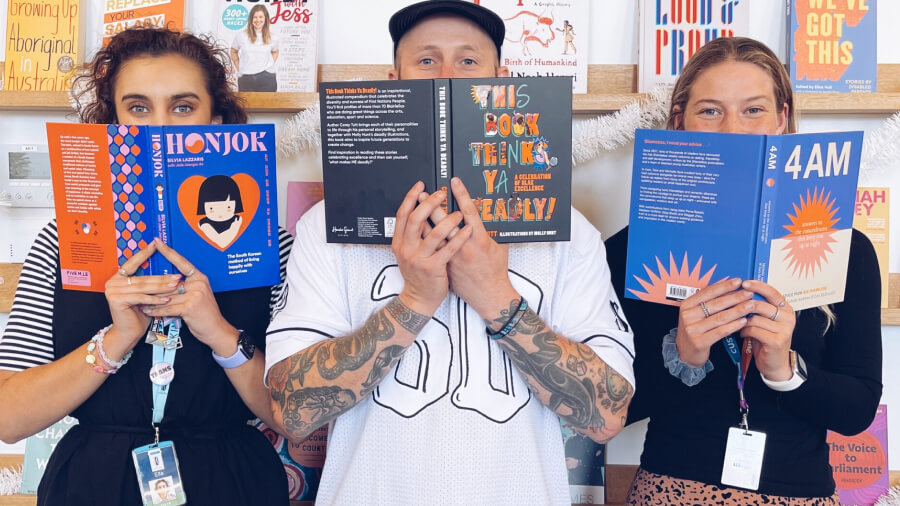 Youth workers holding books in front of their faces in front of the Platform 81 